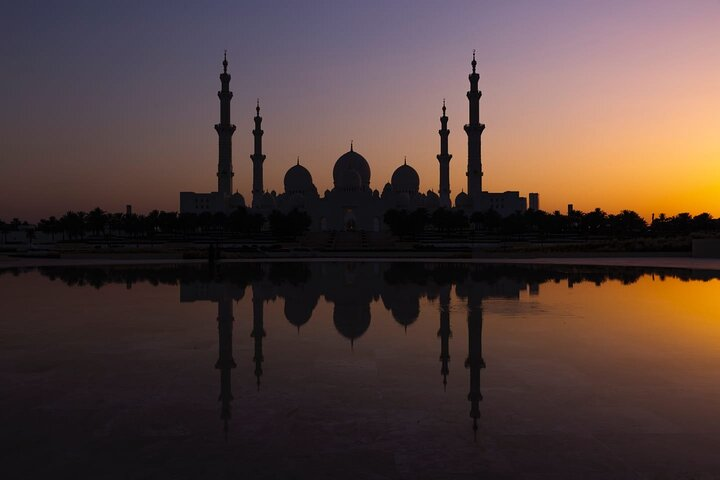 Explore the majestic silhouette of Sheikh Zayed Grand Mosque at sunset where stunning architecture meets reflective pools inviting travelers to experience the beauty and serenity of Abu Dhabi.